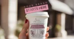 Hand holding a branded takeaway coffee cup featuring a café illustration and logo, with the text ‘Your Brand Starts Here’ above it, symbolizing brand identity and visual branding design.