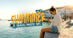Hero banner featuring a woman sitting by the waterfront during golden hour while using her phone, with the title "Summer Travel Photo Tips" overlaid alongside camera and sunglasses illustrations. The image introduces a guide to capturing and editing stunning summer travel photos with beginner-friendly tips.
